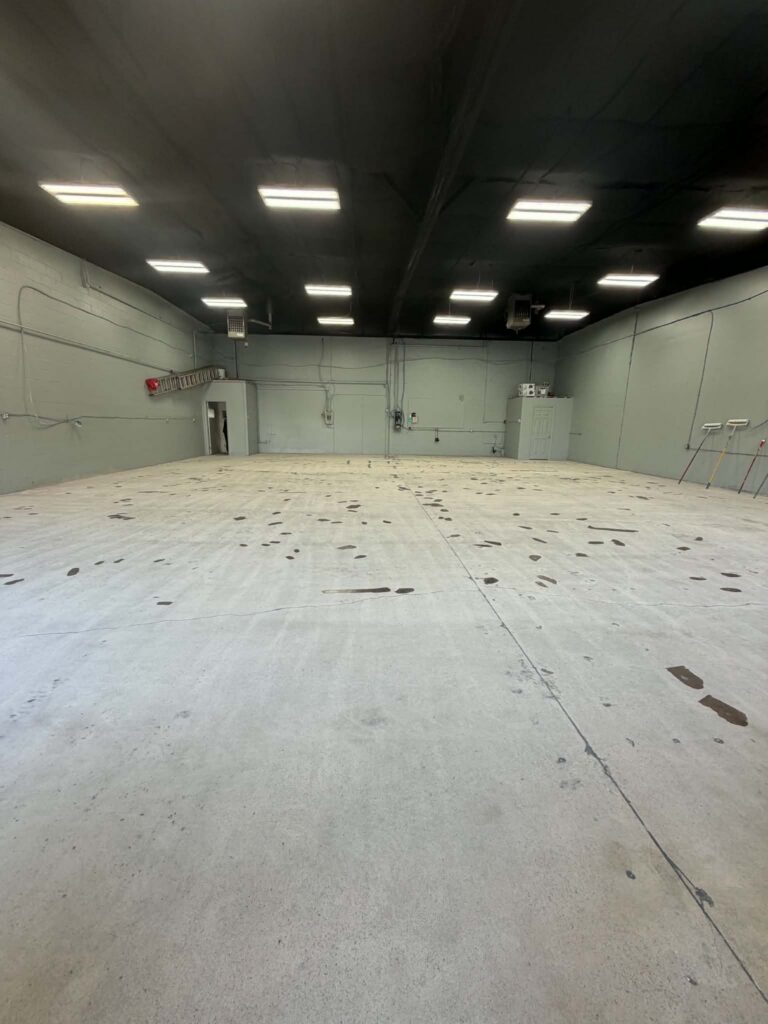 Bare stained concrete shop floor before commercial epoxy coating in Dartmouth, Nova Scotia